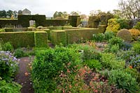 The Flower Garden features strong blocks of box and yew that frame cottage garden plants and flowers, here including poppies, Geraniums and Geum - Herterton House, Hartington, Northumberland, UK