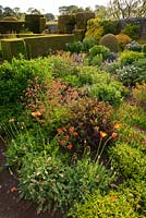 The Flower Garden features strong blocks of box and yew that frame cottage garden plants and flowers, including Geum, Sedum and Hieraciums - Herterton House, Hartington, Northumberland, UK
