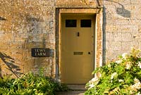 Front door of the Ham stone farmhouse framed with Hydrangea quercifolia - Yews Farm, Martock, Somerset, UK