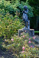 Statue of girl in rose garden. Rosa 'Frau Astrid Spath' in foreground