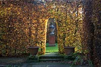 Arched entrance through autumnal beech hedge. East Ruston Old Vicarage Gardens, Norfolk