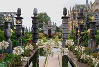 Rill pool flanked by turned oak urns spouting water, with gilded agaves in their tops. Oak columns with stylized acorns on the top frame a view of Oberon's Palace beyond. The Collector Earl's Garden designed by Julian and Isabel Bannerman.