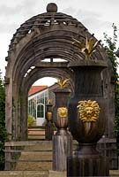 Carved oak urns with gilded lions' heads and agaves with domed pergola beyond in the Collector Earl's Garden designed by Julian and Isabel Bannerman.