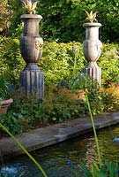 Rill pool flanked by turned oak urns spouting water through gilded lions' heads, with golden agaves in their tops. The Collector Earl's Garden designed by Julian and Isabel Bannerman.