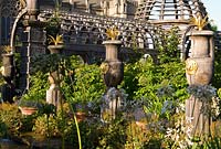 Rill pool flanked by turned oak urns spouting water through gilded lions' heads, with golden agaves in their tops. Oak columns with stylized acorns on the top and domed pergola frame a view of Arundel Cathedral beyond. The Collector Earl's Garden designed by Julian and Isabel Bannerman.