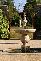 Upper terraces in the Collector Earl's Garden feature fountains with dogs' head spouts, designed by Julian and Isabel Bannerman, with white obelisk glimpsed beyond. 