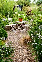 Gravel path with Agapanthus and Aster leading to table and chairs - Brook Hall Cottages, Essex NGS
