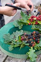 Making an autumn wreath from foraged natural materials - Placing foliage and berries