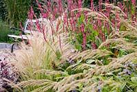 Garden bench and perennial border with Stipa tenuissima, Persicaria amplexicaulis 'Summer Dance' and Achnatherum calamagrostis (Stipa calamagrostis) - Feather Grass, Silver Spear Grass - Garden at Roennede, Denmark