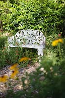 White iron bench surrounded with Rudebeckia laciniata in the Butterfly Garden - Heathcote Botanical Gardens, Florida