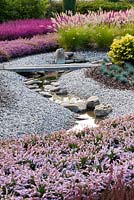 Stream winding through gravel garden with Pennisetum alopecuroides and Calluna vulgaris  - Heathers 
