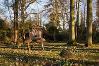 Wooden toadstool sculpture and green oak temple with snow drops in the Stumpery, February 2011.