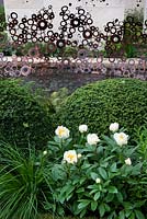 The M&G Garden. Plants include Deschampsia cespitosa, Polystichum 'Braunlaub', Paeonia 'Claire de Lune' and Ilex crenata
