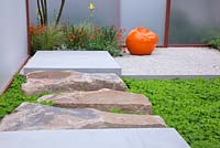 Yorkstone paving cross sunken planting of Galium odoratum leading to a gravel path and seating area enclosed within acrylic screens and planting including Geum, Iris, Stipa tenuissima and Amelanchier lamarckii in The Rainbows Children's Hospice Garden