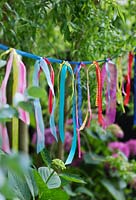 Home made garden bunting made from lengths of colourful ribbons knotted on to a length of ribbon