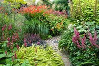 Colourful Summer garden with Persicaria 'Firetail', Hakonechloa macra 'Aureola' Sedum 'Purple Emperor', Crocosmia 'Lucifer', Miscanthus, Astilbe 'Red Sentinel' and Ligularia 'The Rocket'