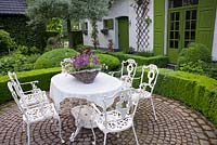 Relaxing area on a paved terrace surrounded with hedging,  De Romantische tuin - The Romantic Garden of Dina Deferme and Tony Pirotte