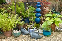 Gravel garden with container planting and decorative ornaments. 