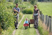 Martin Heutink and his wife Margriet with their two children Nina and Sven walking on the path in the wild garden - Nursery Bloemrijk