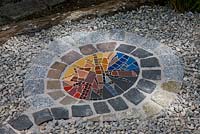 Detail from a mosaic sculpture framed with granite paving