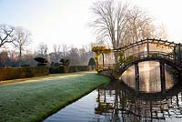 Wooden bridge over moat with Wisteria in winter - Great Fosters, Surrey 