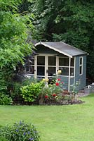 Painted wooden summerhouse in an urban garden with a country feel