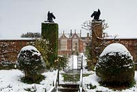 Yew topiary spheres flanking entrance gate to walled garden - Helmingham Hall