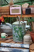 Interior of greenhouse with vintage watering can, radio and pots.