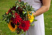 Large Autumnal multicoloured handtied bouquet with Sunflowers, Dahlias, Blackberries and Ivy foliage, held by Georgia Miles of The Sussex Flower School.