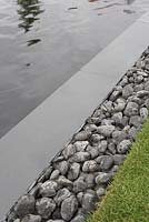 Water, slate, pebbles and grass. Detail from 'Bridge Over Troubled Water'. Hampton Court Flower Show 2012.