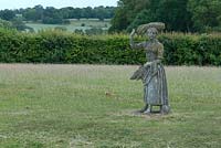 Stone statue of a girl with harvested corn at Wood Farm, Suffolk. June