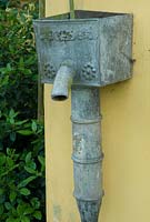 An antique lead pump with a projecting spout and a foliate decorated hopper face. June