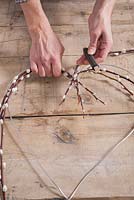 Step-by-step - Using cotton thead to attach branches of Salix caprea, pussy willow to metal frame - making heart shaped decoration