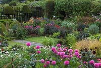 Chenies Manor Gardens, Buckinghamshire, UK - Dahlia Festival. Sunken Garden with Dahlia, Petunia, Sedum spectabile, Sisyrinchium, Leucanthemum, Hosta, Eryngium, Lilium, Anemone x hybrida, Euphorbia and Yew trees