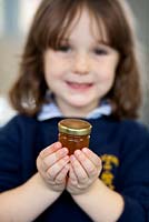 Honey preparation at Hollickwood School. Child with jar of honey
