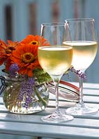Zinnias in old glass preserving jar with two glasses of chilled white wine - Grange Rousseau, Tarn, France