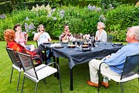 Socialising with friends around table on the lawn by the Crescent Border - Veddw House Garden, Monmouthshire, Wales