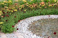 Circular pool with spreading circles of pebbles and planting of Cosmos atrosanguineus, Achillea and  Crocosmia in the 'To The Beat' garden. Gold medal winner and Best Orchestra Garden - RHS Tatton Flower Show 2012