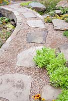Curving path made of gravel and irregular stone slabs in the 'Making a Splash' garden, RHS Tatton Flower Show 2012