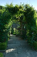 Metal arch leading to gate with Yorkstone path 