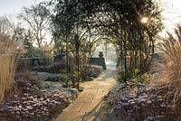 Winter formal garden with Rosa growing over arch, Sedum, Calamagrostis acutiflora and yorkstone paving - Winfield Hse