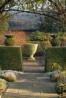 Formal garden in winter with yorkstone path, empty urn and Yew hedge and topiary - Winfield House 