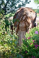 Wood sculpture of Maria, carved in a tree trunk with Asters