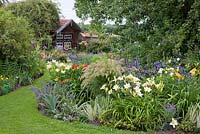 Bavarian country garden in July - perennial borders and a bee house 