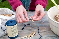 Step by step for creating hanging bird feeders out of teacups and yoghurt pots - tying thread to wooden sticks 