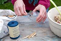Step by step for creating hanging bird feeders out of teacups and yoghurt pots - adding thread for suspending feeder