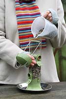 Woman filling up bird feeder with sunflower seeds