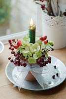 Table candle decorations made of Hydrangea flowerheads, rosehips and autumn berries in terracotta pots