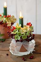 Table candle decorations made of hydrangea flowerheads, rosehips and autumn berries in terracotta pots