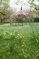 Decorative gazebo in The Lake Field amongst spring flowers - West Green House, Hampshire